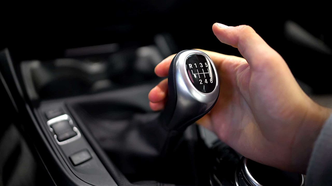 Why should you not touch the lever of a manual transmission while driving?
