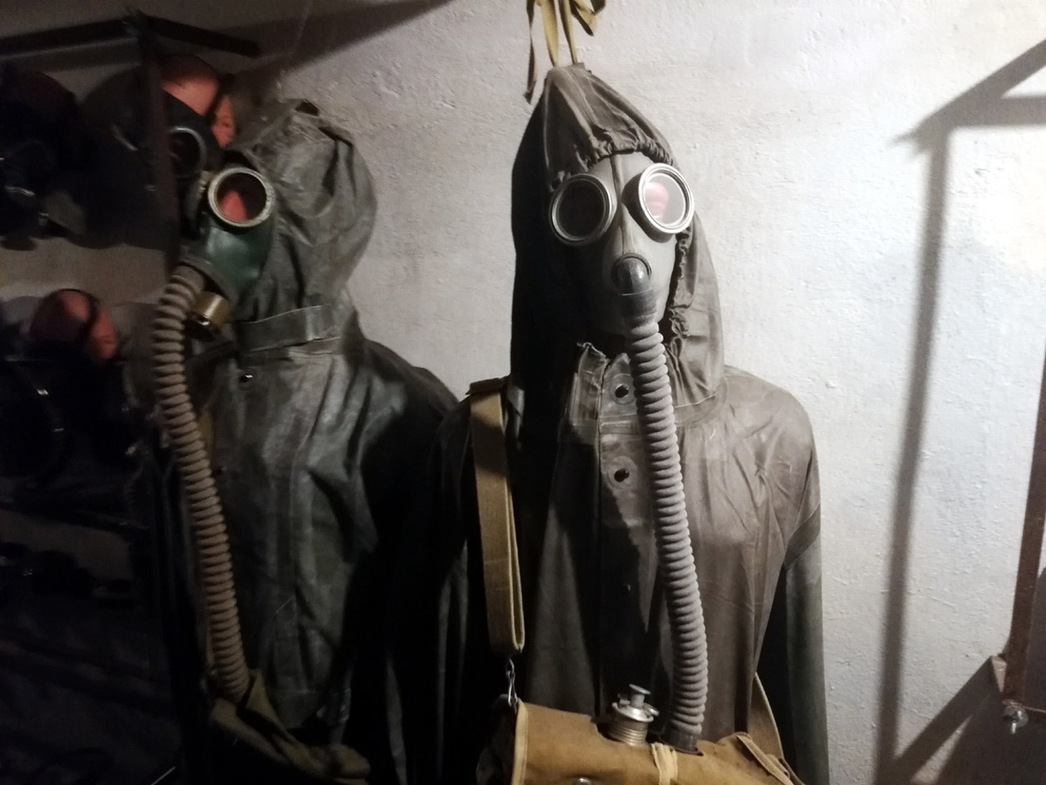 Жутковатого вида костюмы химзащиты висят вдоль проходов